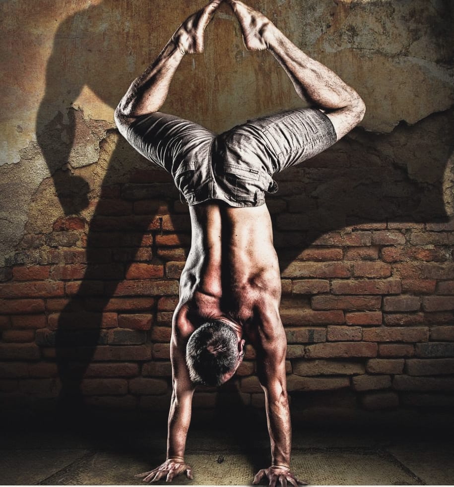Mat Harvey in a handstand in front of a brick wall