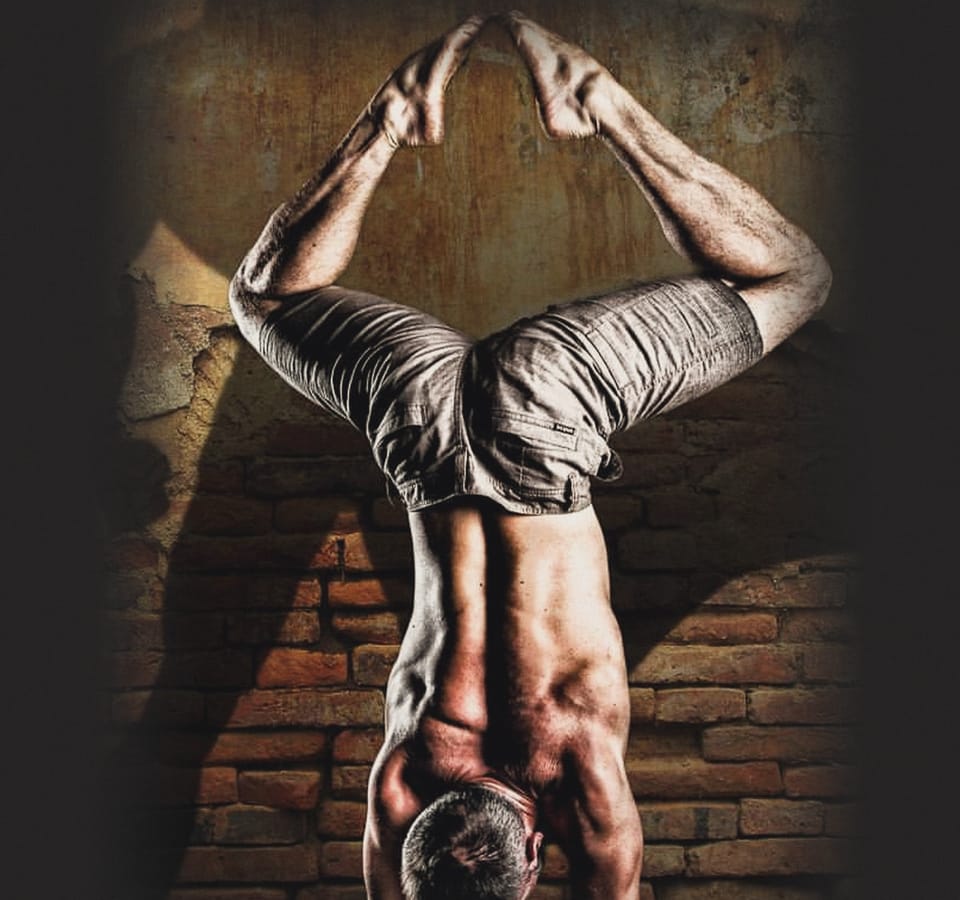 Mat Harvey in a handstand against a brick wall, the photograph on the cover of The Handstand